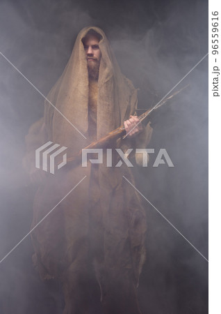 man in a vintage monk costume with a wooden ax in a haze, cosplay for ancient times, a historical plot 96559616