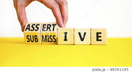 Submissive or assertive symbol. Concept words Submissive and assertive on wooden cubes. Businessman hand. Beautiful white background. Business, psychological submissive assertive concept. Copy space. Submissive or assertive symbol. Concept words Submissive and assertive on wooden cubes. Businessman hand. Beautiful white background. Business, psychological submissive assertive concept. Copy space. 96561195