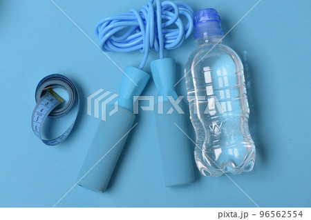 Skipping rope in cyan color on blue background, top view. Skipping rope in cyan color on blue background, top view. 96562554
