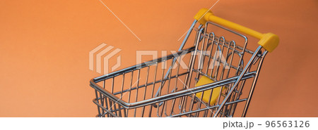 Empty shopping trolley cart on beige background. Copy space for your text. Online shopping, buy mall market shop consumer concept. Small toy supermarket grocery push cart. Food crisis. Rising food Empty shopping trolley cart on beige background. Copy space for your text. Online shopping, buy mall market shop consumer concept. Small toy supermarket grocery push cart. Food crisis. Rising food 96563126
