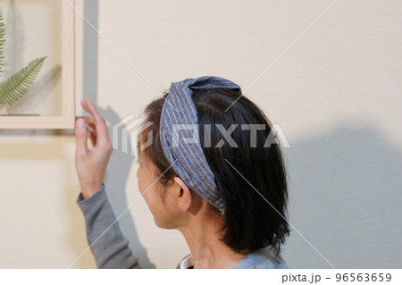 ボタニカルフレームを飾るクロスヘアバンドをした中年女性 96563659