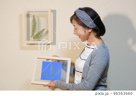 ボタニカルフレームを飾るクロスヘアバンドをした中年女性 96563660