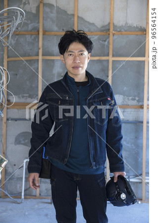 お洒落なデニム作業着を着て建築現場に立つ作業員男性 お洒落なデニム作業着を着て建築現場に立つ作業員男性 96564154