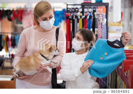 Woman in mask in pet store during shopping with her daughter with dog Woman in mask in pet store during shopping with her daughter with dog 96564891
