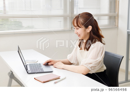 オフィスやレンタルスペースでパソコンを操作する女性。オンラインで快適に仕事をするイメージ。 96566498