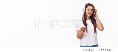 Technology, lifestyle and music concept. Portrait of pleased and relaxed young woman vibing and chilling as listening favorite song in headphones, hold mobile phone, smile and close eyes Technology, lifestyle and music concept. Portrait of pleased and relaxed young woman vibing and chilling as listening favorite song in headphones, hold mobile phone, smile and close eyes 96566611