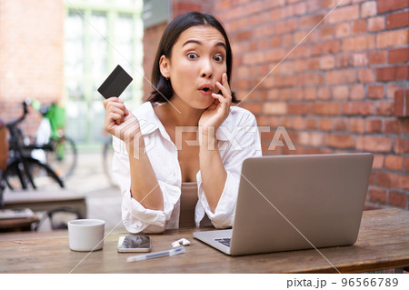 Stylish young asian woman doing shopping online, sitting with credit card and laptop, buying in internet and paying contactless, dealing with bills Stylish young asian woman doing shopping online, sitting with credit card and laptop, buying in internet and paying contactless, dealing with bills 96566789