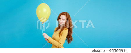 Celebrating Concept - Close up Portrait happy young beautiful attractive redhair girl smiling with colorful party balloon. Blue Pastel Background. 96566914