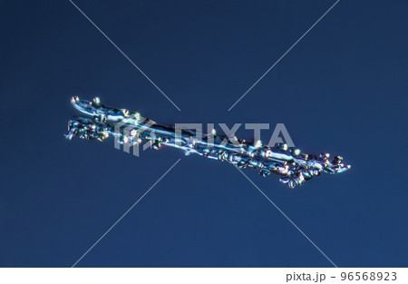 Real needle snowflake at high magnification. Macro photo of small rimmed snow crystal, snowflake glowing on dark blue background 96568923