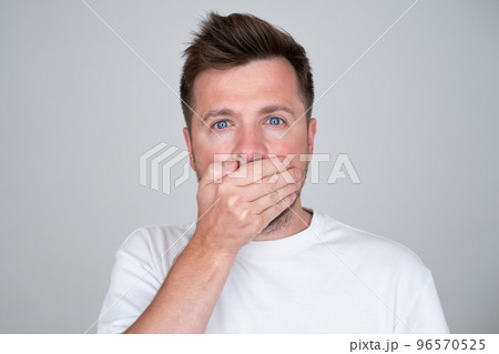Keeping your secret. man covering mouth with hand and looking at camera. Keeping your secret. man covering mouth with hand and looking at camera. 96570525