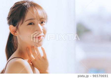 朝日を浴びてスキンケアをしている若い女性の写真 96570691