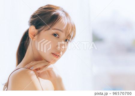 朝日を浴びてスキンケアをしている若い女性の写真 96570700