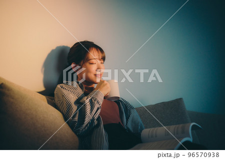 夕日を浴びながら読書をする若い女性の写真 96570938