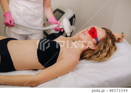 A girl in black underwear gets laser hair removal on her body in the salon 96571544