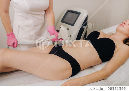 A girl in black underwear gets laser hair removal on her body in the salon 96571546