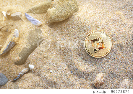 Binance coin on the beach sand with shells and stones. Single golden crypto BNB banner in warm tones with copy space top view. Summer vibe. Environment impact of mining cryptocurrency concept. Binance coin on the beach sand with shells and stones. Single golden crypto BNB banner in warm tones with copy space top view. Summer vibe. Environment impact of mining cryptocurrency concept. 96572874