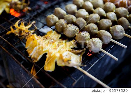 Top view of meatballs and squid grilled skewers placed Thai street food favorites, focus selective Top view of meatballs and squid grilled skewers placed Thai street food favorites, focus selective 96573520