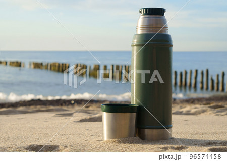Thermos with tea on the background of nature. Drinking tea on the seashore. 96574458
