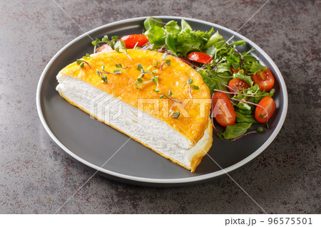 Delicate french Poulard omelette with beaten egg whites served with fresh salad close-up on a plate. horizontal Delicate french Poulard omelette with beaten egg whites served with fresh salad close-up on a plate. horizontal 96575501