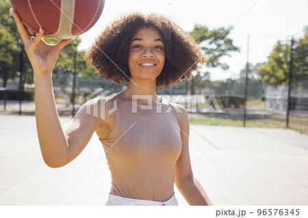 Stylish cool teen girl gathering at basketball court, playing basketball outdoors Stylish cool teen girl gathering at basketball court, playing basketball outdoors 96576345