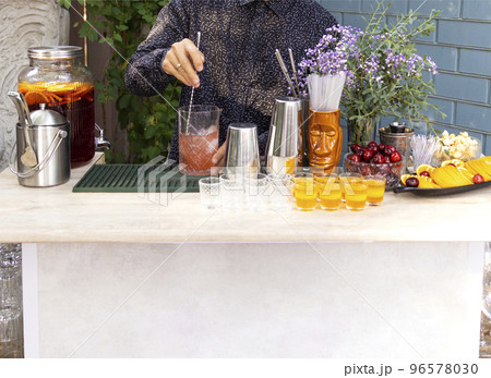 Glasses of cocktails on the bar. Bartender pours a glass of sparkling wine with red alcohol. Glasses of cocktails on the bar. Bartender pours a glass of sparkling wine with red alcohol. 96578030