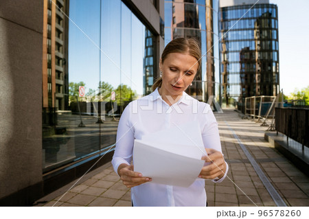 Business woman with papers in hand against the background of the office center Business woman with papers in hand against the background of the office center 96578260