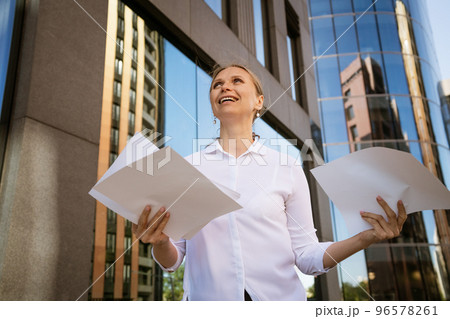 Business woman with papers in hand against the background of the office center 96578261