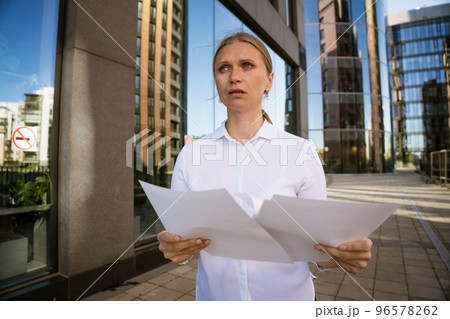 Business woman with papers in hand against the background of the office center Business woman with papers in hand against the background of the office center 96578262