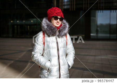 Happy young woman in winter jacket with backpack near building Happy young woman in winter jacket with backpack near building 96578447