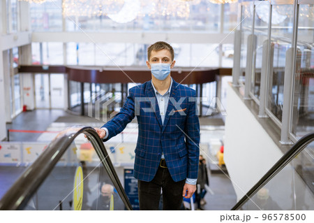 Young man wearing a mask climbs the escalator in the mall 96578500