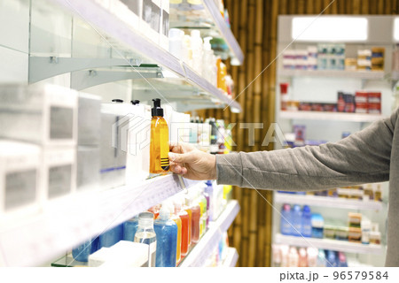 Male customer choosing a men's hair product from the supermarket shelf 96579584