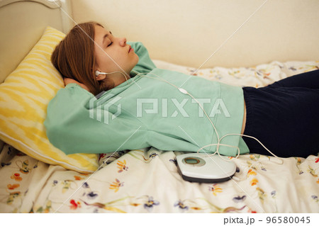 Teenage girl displaying CD and listening to music iin her room Teenage girl displaying CD and listening to music iin her room 96580045