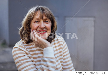 Happy smiling senior blonde woman in colorful yellow and white top 96580071