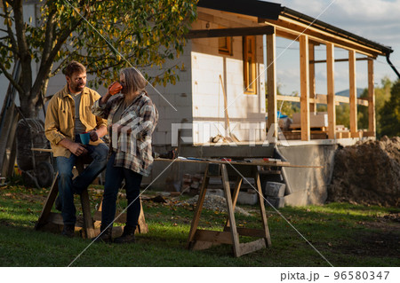 Mature couple having coffee break when working together on construction site of their new house. 96580347