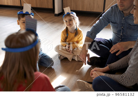 Happy young family with kids playing a card game at home sitting on the floor 96581132