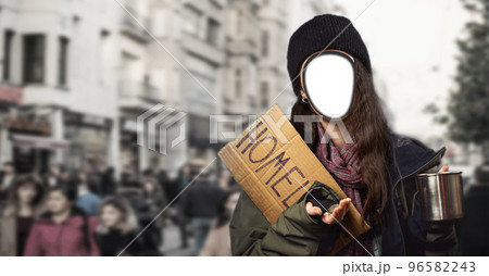 A vagabond woman holds a cardboard sign with the inscription homeless and a steel begging cup. A cutted out face. The concept banner of every person can become a homeless A vagabond woman holds a cardboard sign with the inscription homeless and a steel begging cup. A cutted out face. The concept banner of every person can become a homeless 96582243