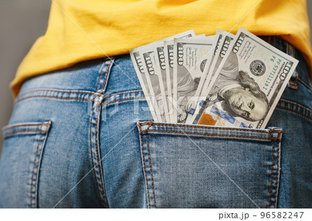 One hundred-dollar bills sticking out of the back pocket of jeans, close-up, rear view. The concept of wages, savings and wealth 96582247