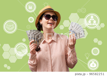 Investment. A rich happy joyful woman in glasses and a straw hat holds fans of American dollars. Green background with digital service. Concept of money remittance and cryptocurrency Investment. A rich happy joyful woman in glasses and a straw hat holds fans of American dollars. Green background with digital service. Concept of money remittance and cryptocurrency 96582251