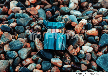 International Fragrance Day. Blue glass perfume bottle on a wet pebble beach. Top view. Close-up. Perfume advertising concept 96582396