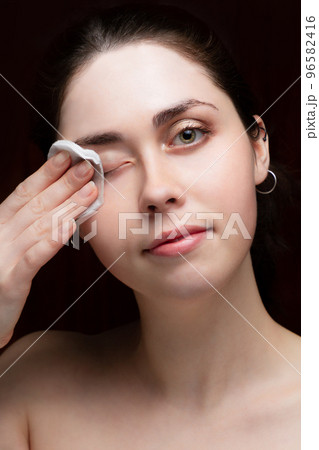 Beautiful girl cleans her face from makeup. Black background Beautiful girl cleans her face from makeup. Black background 96582416