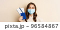 Travel and covid-19 pandemic. Close up portrait of smiling woman in medical mask, showing passport with two tickets, concept of tourism, beige background 96584867