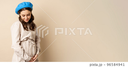 Pregnant woman. Young beautiful girl expecting baby, holding hands on belly and smiling tenderly, concept of surrogacy and pregnancy 96584941
