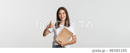 Cheerful smiling girl holding notebooks and showing thumbs-up, recommend courses or school 96585195