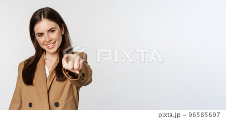Portrait of smiling enthusiastic businesswoman, saleswoman pointing finger at camera and choosing, inviting you, standing over white background 96585697