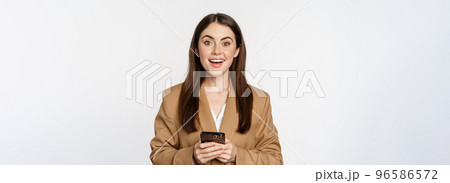 Smiling businesswoman using smartphone, app on mobile phone, standing over white background 96586572