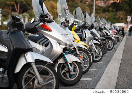 many scooters and motorcycles are parked in a long row. many scooters and motorcycles are parked in a long row. 96586666