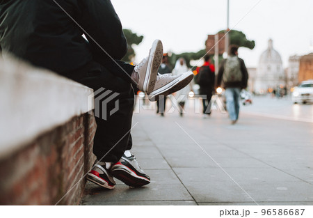 teenage boy and girl sit together on the street where you can see their legs. teenage boy and girl sit together on the street where you can see their legs. 96586687