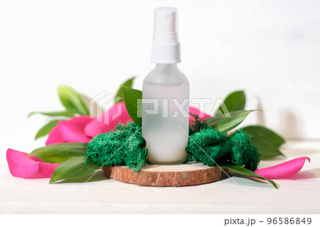 Mock up glass spray bottle on wooden saw cut podium with rose petals and moss and leaves. beauty fermented cosmetic skin care product,  96586849