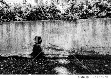 Stormwater drain outlet in an urban area with seepage discoloring a concrete barrier Stormwater drain outlet in an urban area with seepage discoloring a concrete barrier 96587076