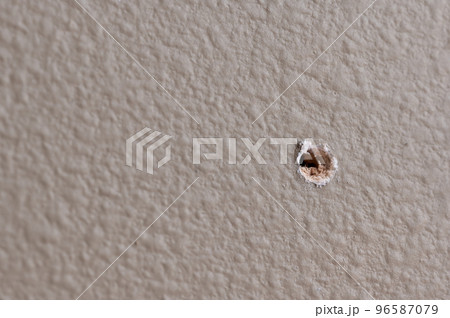 Selective focus on drilled hole through drywall with bits of insulation showing. Selective focus on drilled hole through drywall with bits of insulation showing. 96587079